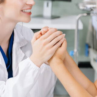 Hand of doctor touching aged patient to support and reassure her
